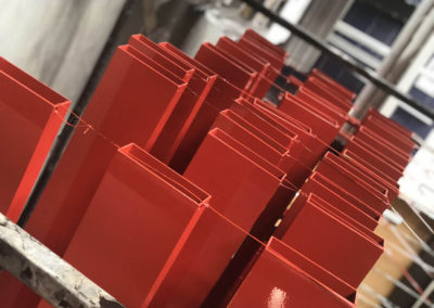 Lengths of Aluminium powder coated in flame red stacked drying racks