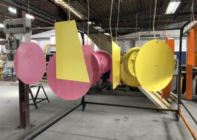 Playground equipment hung to dry after being powder coated in two colours yellow and pink