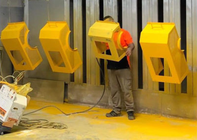 Industrial machine safety covers in the process of being powder coated safety yellow by a skilled spray painter(powder coating) specialist